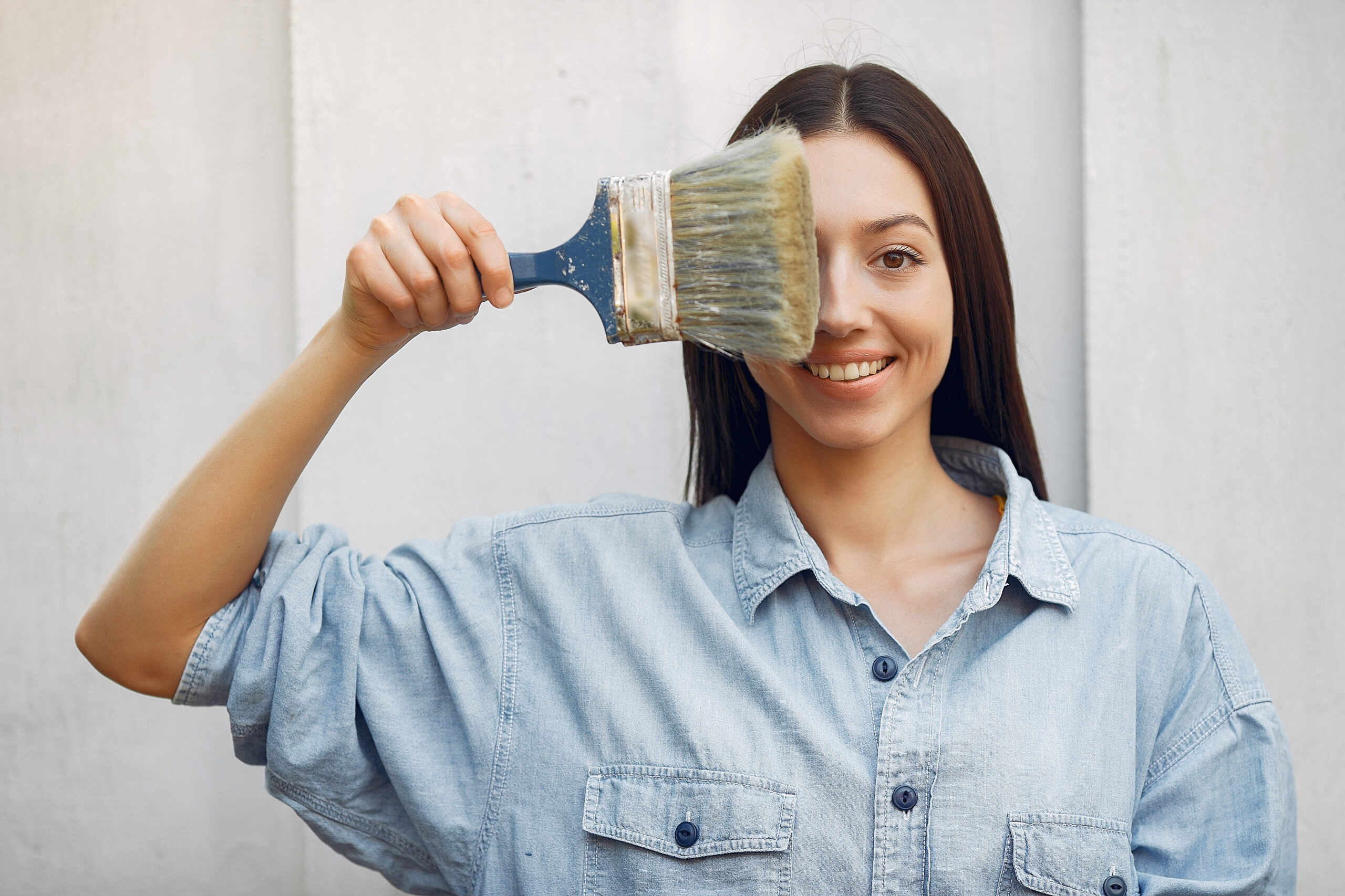 Cute girl standing near wall with repair tools